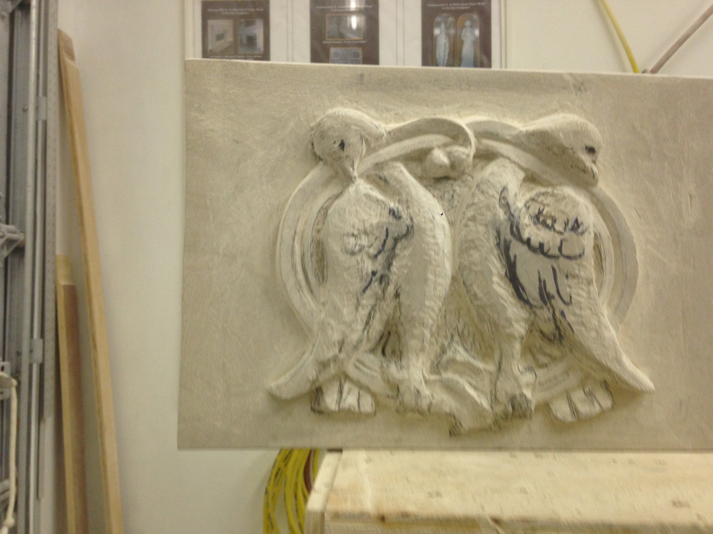 Le relief aux oiseaux vu de face à l'atelier, le plumage en cours de taille.