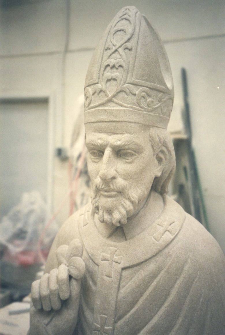 Close-up of the carved limestone Saint Patrick — face and mitre, photographed from the front.