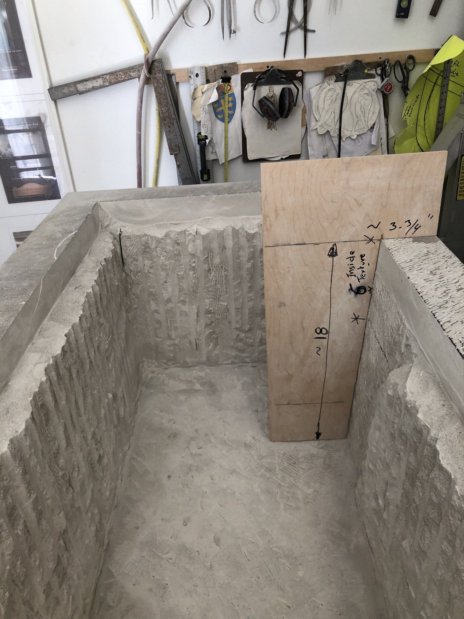L'intérieur en cours de creusement, les parois encore striées de traces de ciseau, un gabarit en contreplaqué annoté de cotes dressé à l'intérieur.