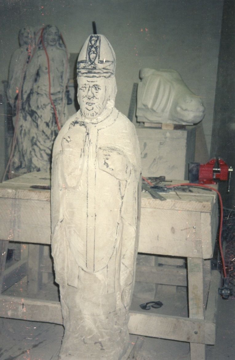 Saint Patrick figure being carved in the workshop, partially complete with chisel marks still visible.