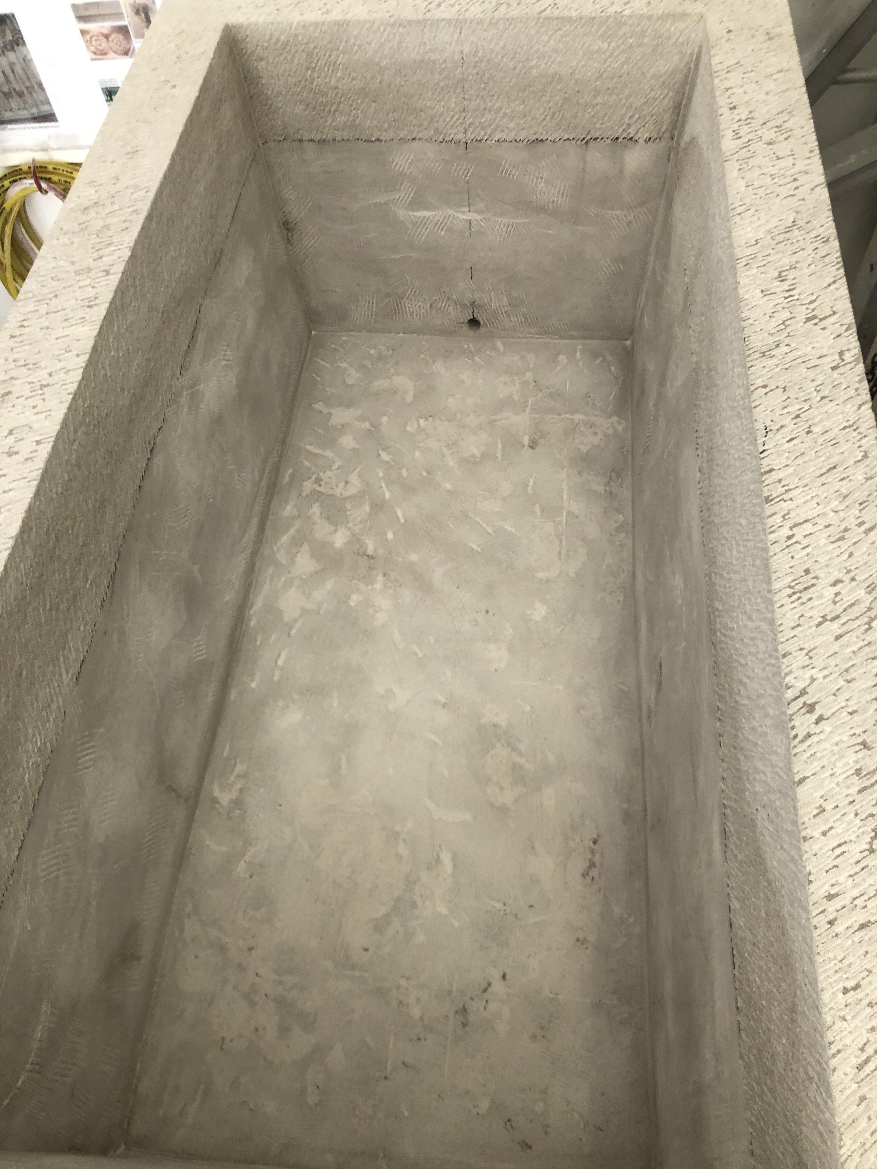 Looking down into a deep rectangular limestone planter in the studio: smooth inner walls and floor, the top edge with a tooled finish.