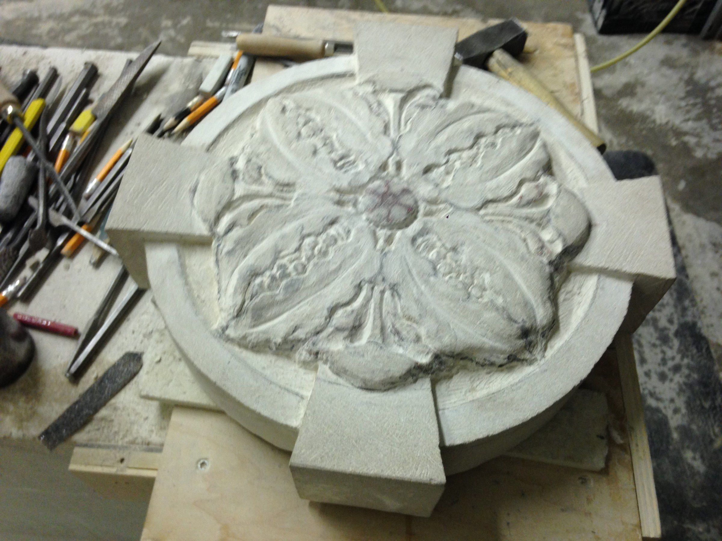 A rosette carved with four broad leaves around a small center, its arms still square-cut.
