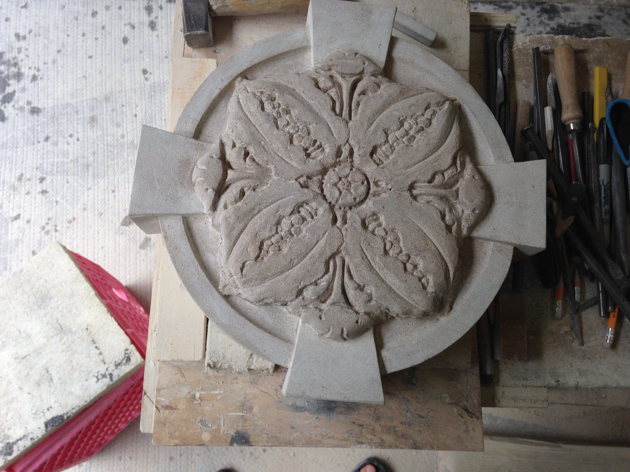 A rosette with four pointed petals edged with beading, seen from above on the bench.