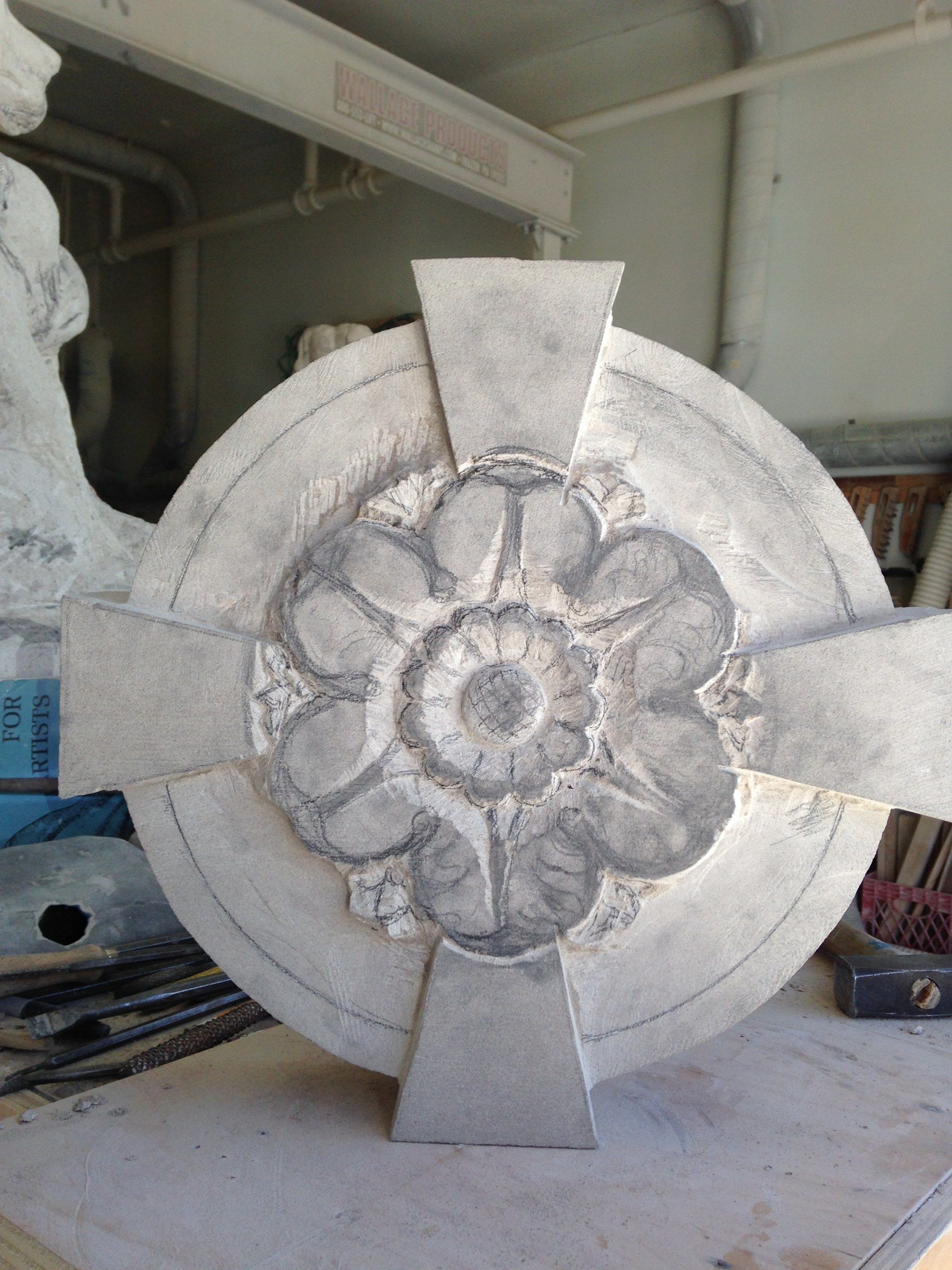 A rosette standing upright in the studio, a lobed flower roughed out inside the round frame.