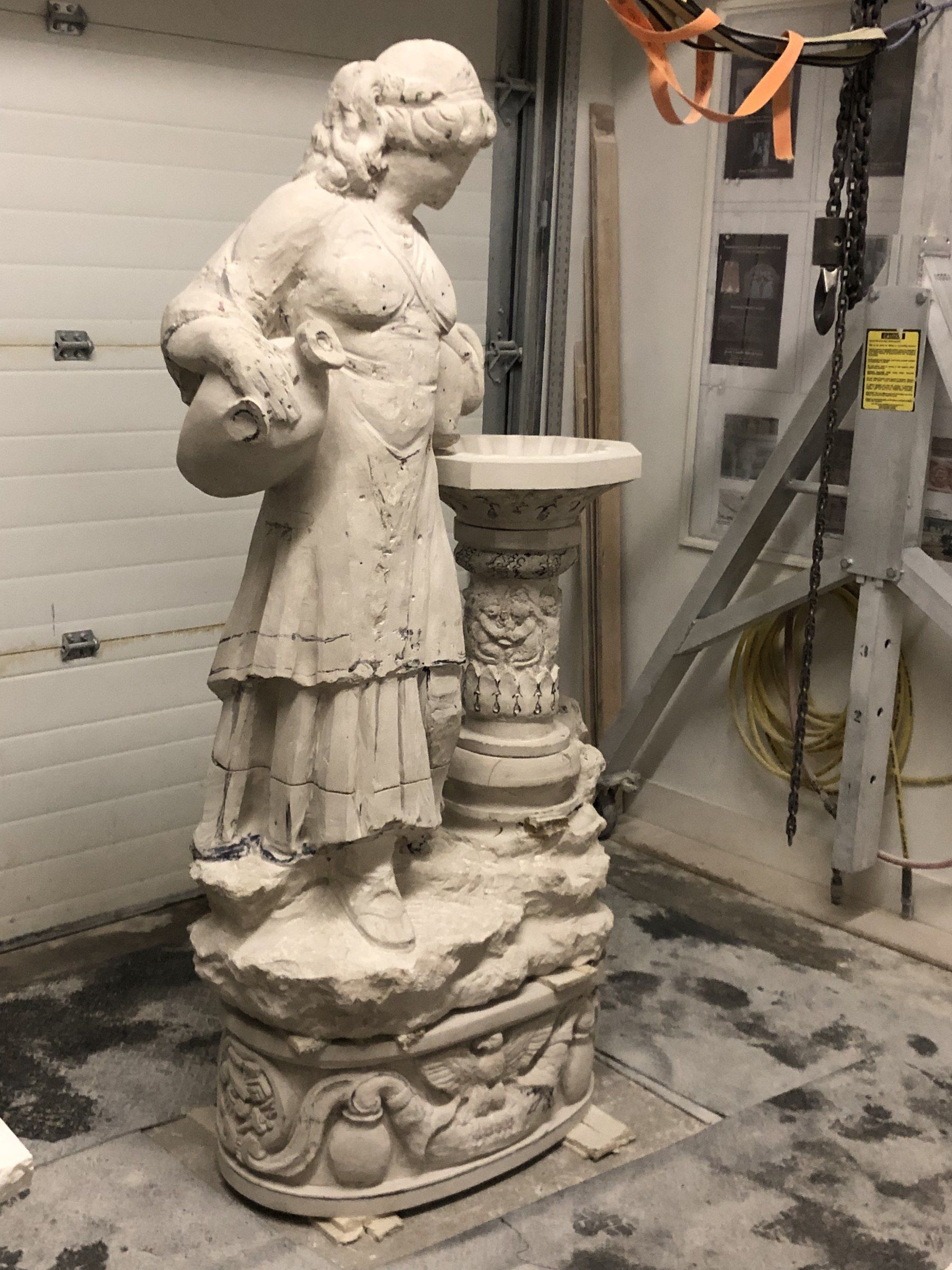The fountain seen from the side in the studio, standing on its carved oval pedestal.