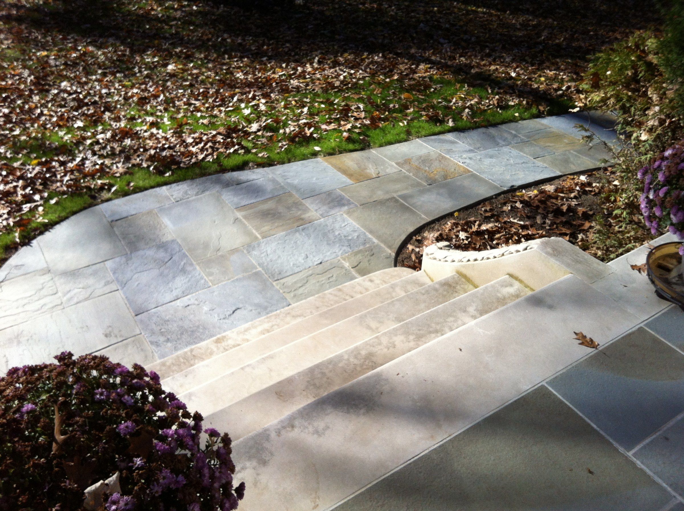 The steps seen from the top, the stone path curving away across the lawn, with potted chrysanthemums in the foreground.