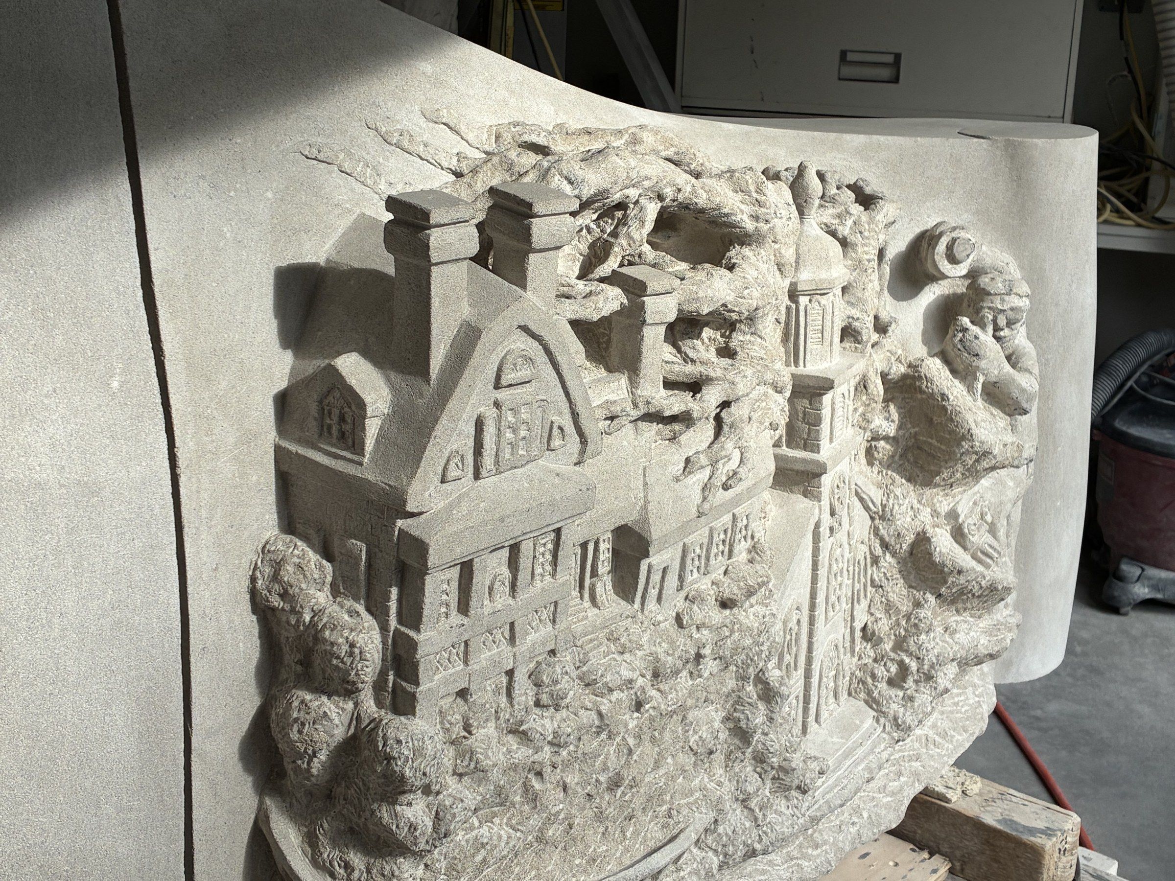 Close-up in September 2026 of the Zabriskie House carved on the Wyckoff face — the colonial Dutch house also shown on the township's coat of arms: a gambrel roof, tall chimneys and rows of windows, among carved trees, beside the steeple of the Wyckoff Reformed Church.